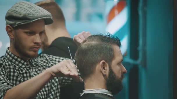 Barber zastřihne vlasy klienta s nůžkami - Záběry, video