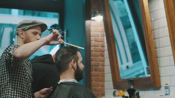 Barber zastřihne vlasy klienta s nůžkami - Záběry, video