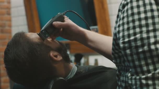 Peluquero afeitar la barba del cliente con trimmer
 - Imágenes, Vídeo