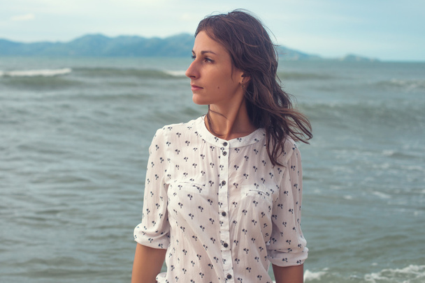 Молода жінка стоїть біля моря
 - Фото, зображення