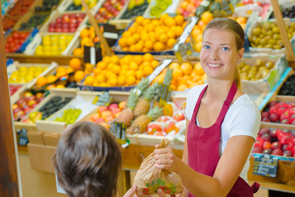 Shop assistant serving customer in grocers - 写真・画像