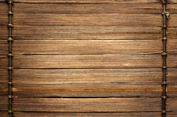 Bamboo sticks brown wooden background with thread uniting. - Zdjęcie, obraz