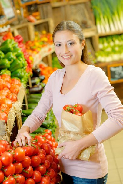 Lady holding paper bag full of tomatoes - Фото, изображение