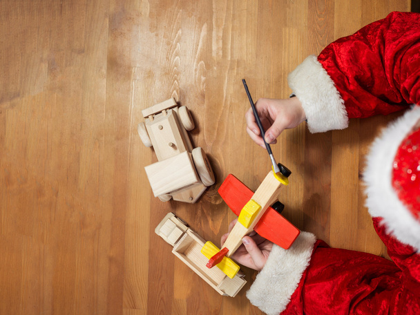 Santa Claus making toys. Painting and coloring wooden toy - Fotografie, Obrázek