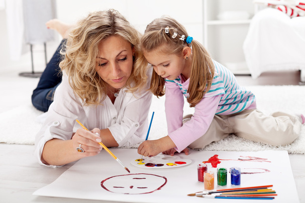 Little girl painting with her mother - Фото, изображение