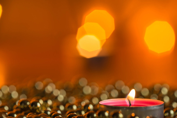 Burning candle and Christmas ornaments with bokeh in the background - Foto, Imagen