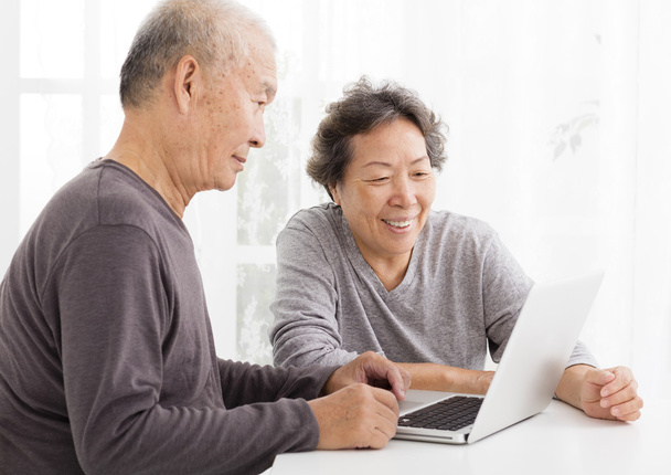 felice coppia di anziani utilizzando il computer portatile in soggiorno
 - Foto, immagini