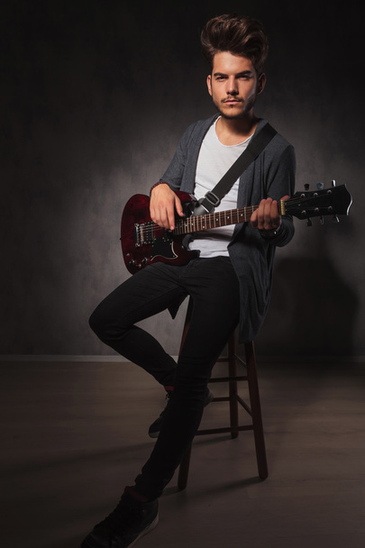 artista em forma tocando guitarra em estúdio enquanto sentado
 - Foto, Imagem