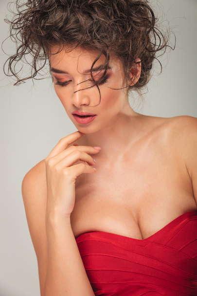μοντέλο στο κόκκινο φόρεμα πόζα, αγγίζοντας το πηγούνι της - Φωτογραφία, εικόνα