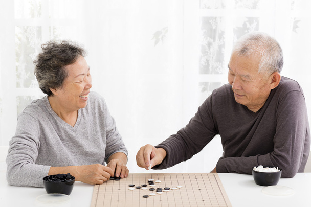 glückliches asiatisches Seniorenpaar spielt Schach im Wohnzimmer - Foto, Bild
