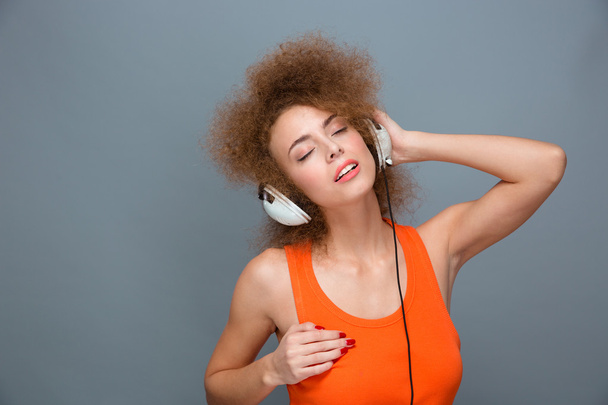 Relaxed carefree curly woman in earphones listening to music  - Foto, afbeelding
