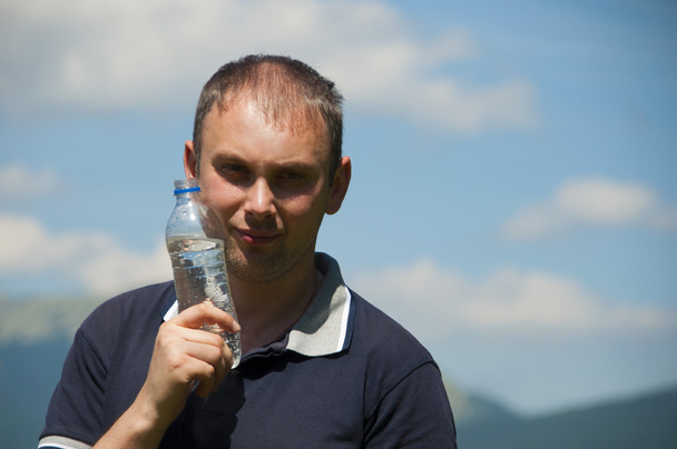 ein Mann mit einer Flasche Wasser auf dem Berg - Foto, Bild
