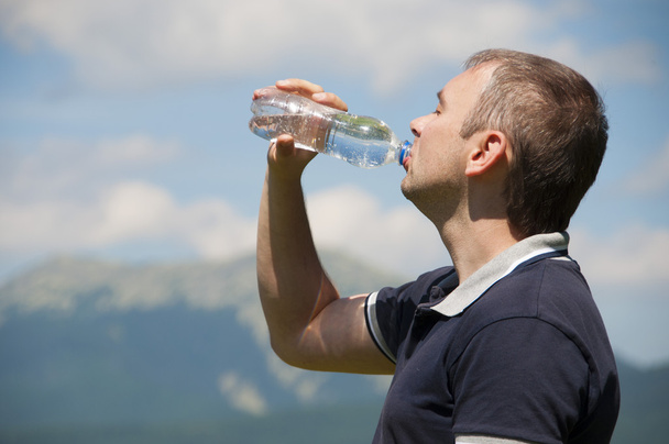 Чоловік п'є воду з пляшки в горах
 - Фото, зображення