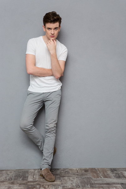 Thoughtful young guy standing on gray background - Fotografie, Obrázek