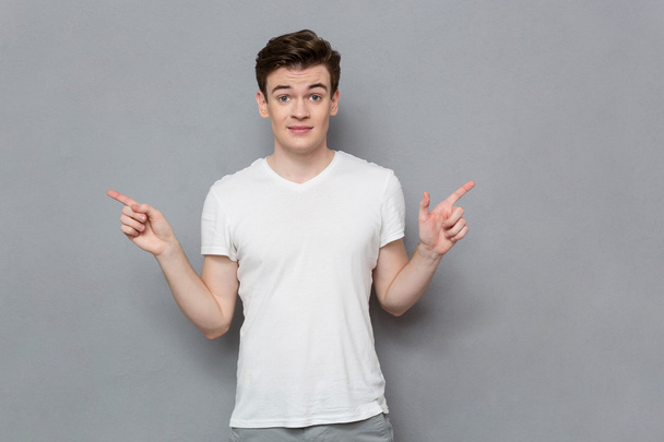 Confused young man showing fingers in different directions  - Photo, image