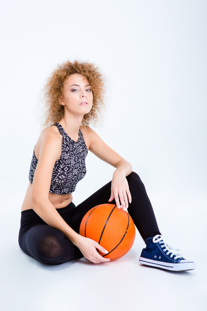 Sports woman sitting on the floor with basketball ball - Foto, Imagen