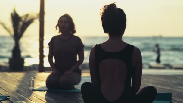 dwie kobiety medytuje na plaży zwolnionym tempie - Materiał filmowy, wideo