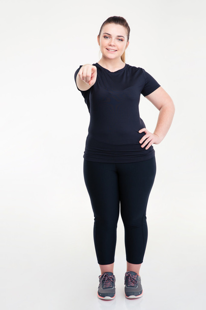 Happy fat woman in sportswear pointing finger at camera - Foto, afbeelding