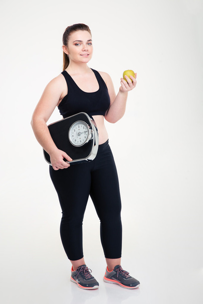 Happy fat woman holding weighing machine and apple - Φωτογραφία, εικόνα