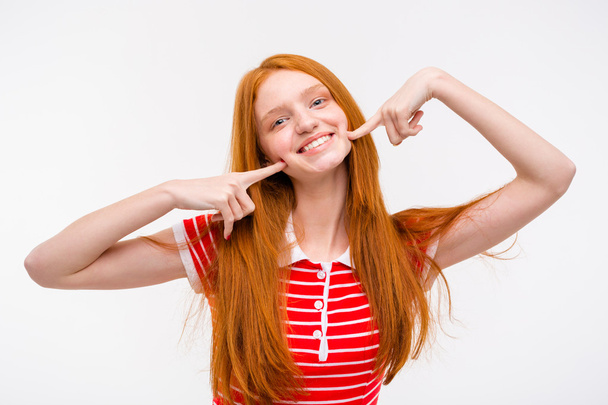 Positive redhead young woman touching her cheeks with fingers  - Φωτογραφία, εικόνα