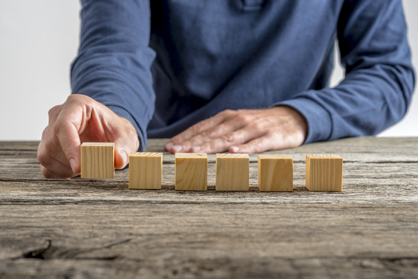 Man placing six blank wooden cubes in a row - Photo, Image