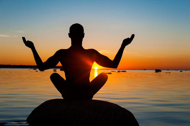 Meditando uomo silhouette su sfondo multicolore tramonto
. - Foto, immagini