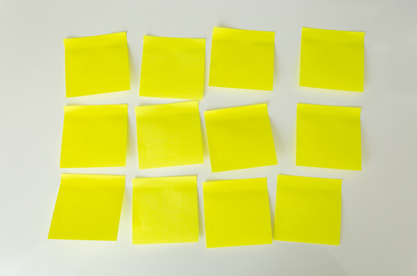 Closeup of 12 blank yellow sticky notes on white board - Fotó, kép