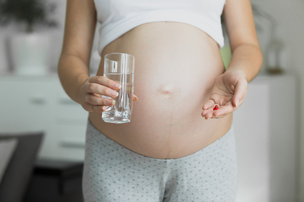 Toned photo of pregnant woman with glass of water and pills - Foto, Imagem