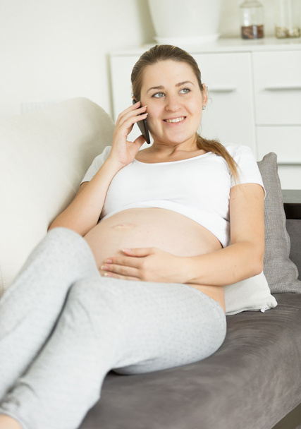 mujer embarazada sentada en el sofá y hablando por teléfono
 - Foto, Imagen