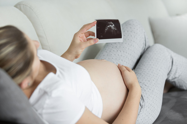 Nahaufnahme einer schwangeren Frau beim Betrachten eines Ultraschall-Embryo-Bildes - Foto, Bild