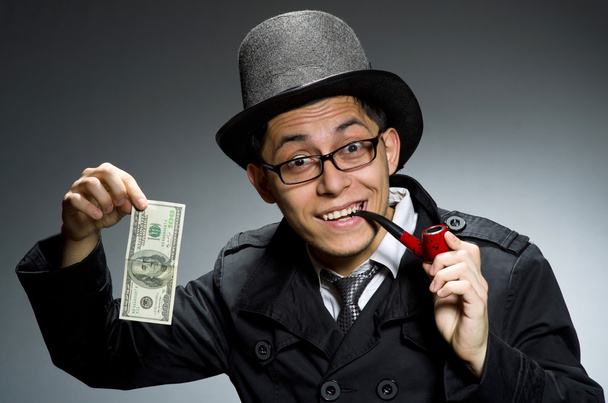 Junge Detektivin im schwarzen Mantel mit Geld gegen Grau - Foto, Bild