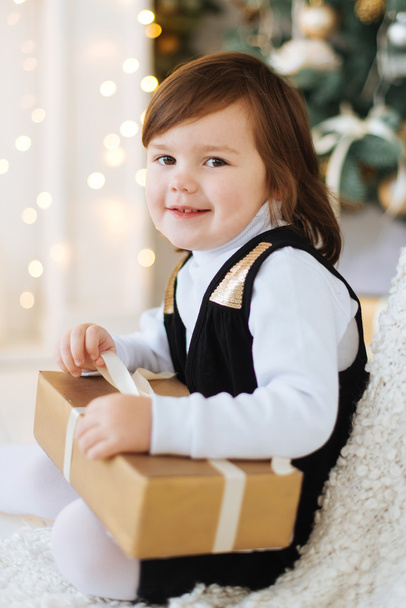 Mała dziewczynka uśmiechający się w pobliżu choinki i prezenty. - Zdjęcie, obraz