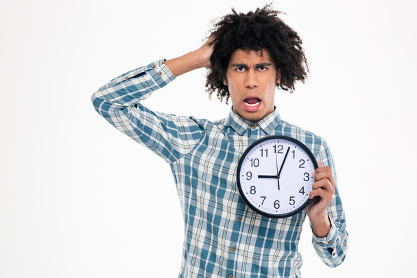 Shocked afro american man holding wall clock - Фото, изображение