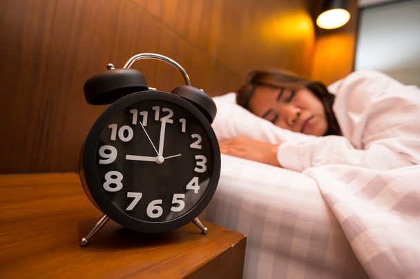 Aziatische vrouw slapen in bed en wekker - Foto, afbeelding