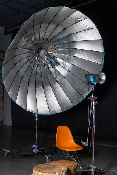 Empty photo studio with modern interior and lighting equipment. Preparation for studio shooting: empty chair and studio lighting. - Photo, image