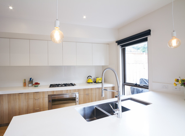 Moderne keuken met hanger verlichting en gezonken wastafel - Foto, afbeelding