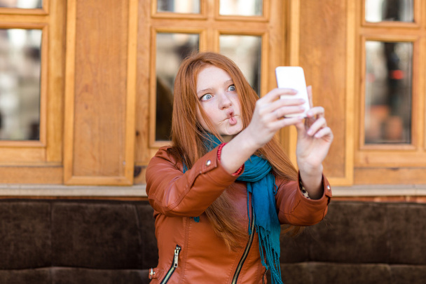 Amusing girl making funny faces and taking photos of herself  - Fotoğraf, Görsel