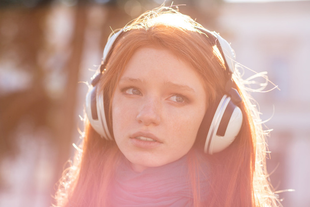 Closeup of thoughtful pretty young lady in headphones - Фото, зображення