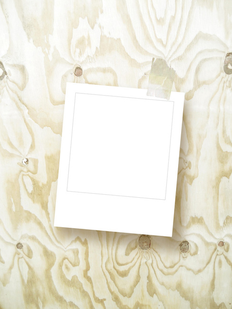 Single blank square instant photo frame with scotch tape on light brown wooden board - Photo, Image
