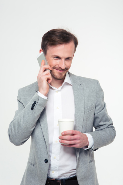 Businessman holding cup with coffee and talking on the phone - Zdjęcie, obraz
