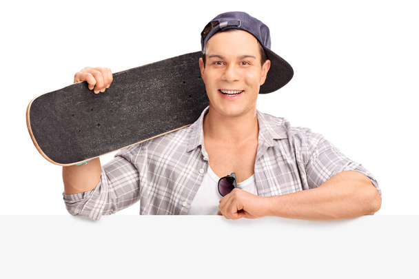 Cheerful skater posing behind a billboard  - Фото, изображение