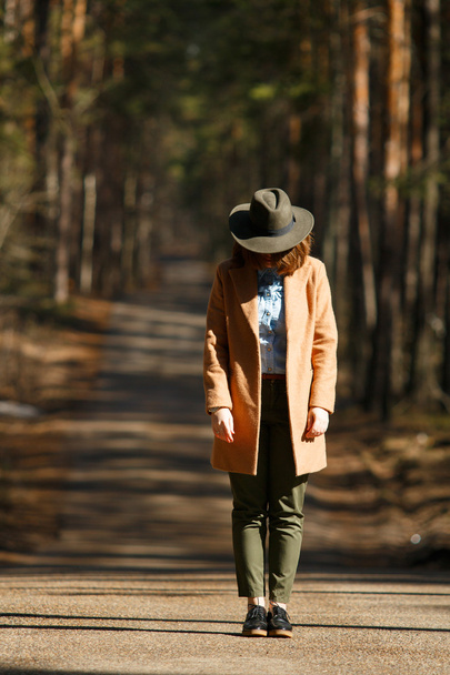 Girl in a hat stands on the way of forest trees - Fotografie, Obrázek