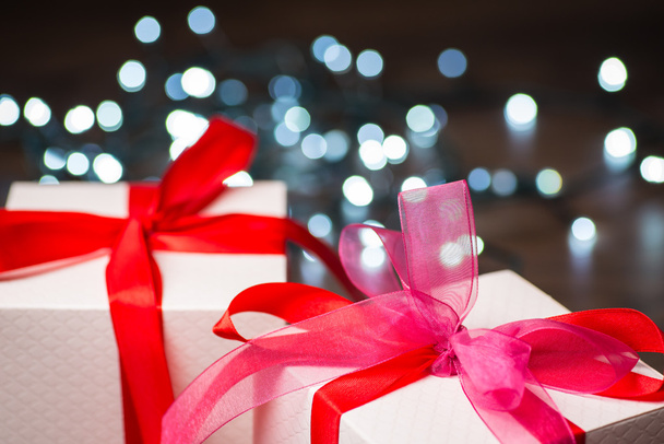 Κουτιά δώρων Χριστουγέννων με κόκκινο τόξο και φώτα σε ξύλινη επιφάνεια - Φωτογραφία, εικόνα