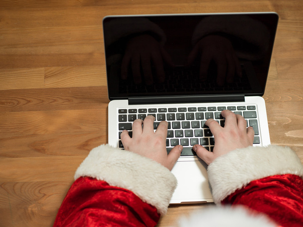 Santa working at desk and typing on a laptop, Christmas gifts an - Valokuva, kuva