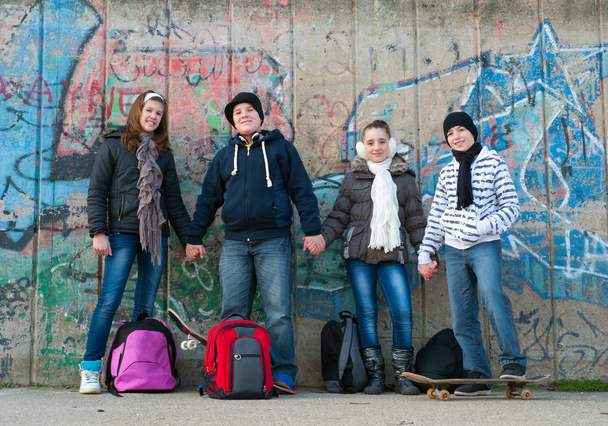 Happy teenage friends with school bags and skateboards standing in front of - Photo, Image