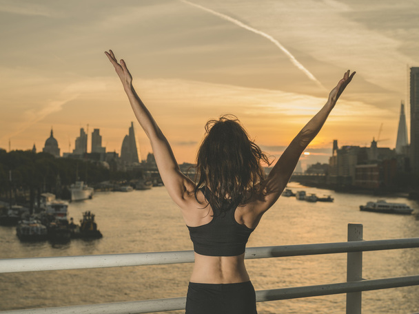 glücklich athletische junge Frau mit erhobenen Armen bei Sonnenaufgang - Foto, Bild