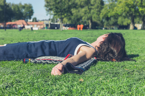 Young woman relaxing on the grass in a park - 写真・画像