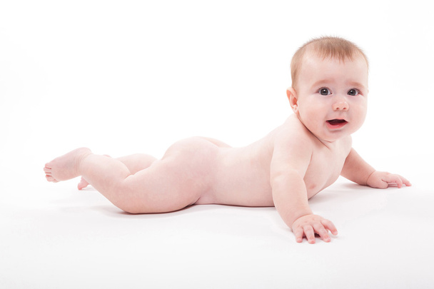 Desnudo sonriente bebé acostado sobre su estómago sobre un fondo blanco un
 - Foto, imagen
