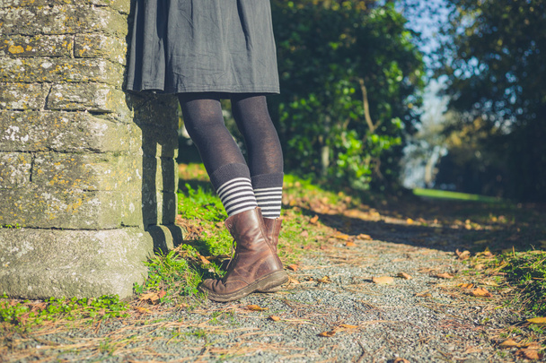 Ноги молодої жінки в сільській місцевості біля стіни
 - Фото, зображення