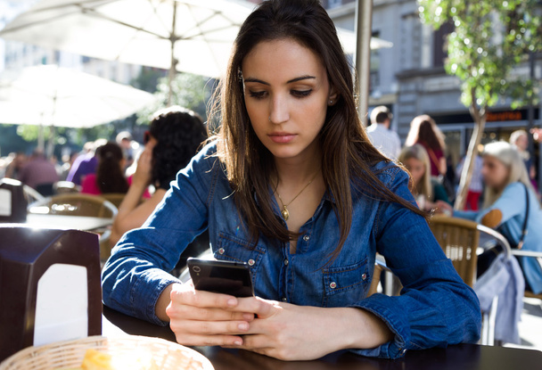 Красивая молодая женщина использует свой мобильный телефон на улице
. - Фото, изображение